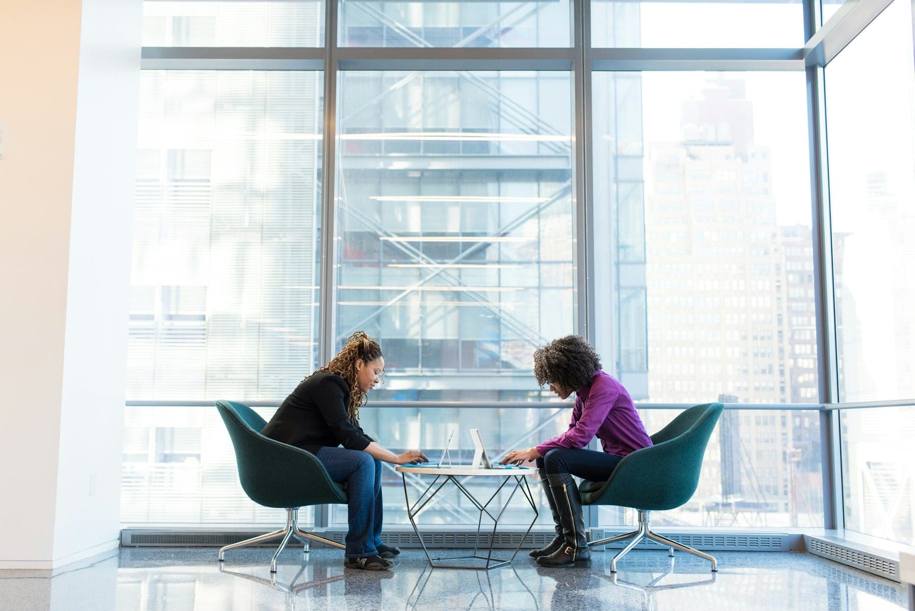 Two people in conversation at a small table beside a window.
