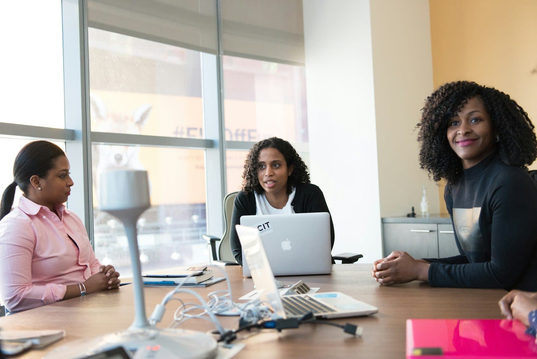 Three colleagues reviewing figures together at a desk with a laptop.